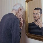 Oudere man kijk naar zijn jongere zelf in de spiegel